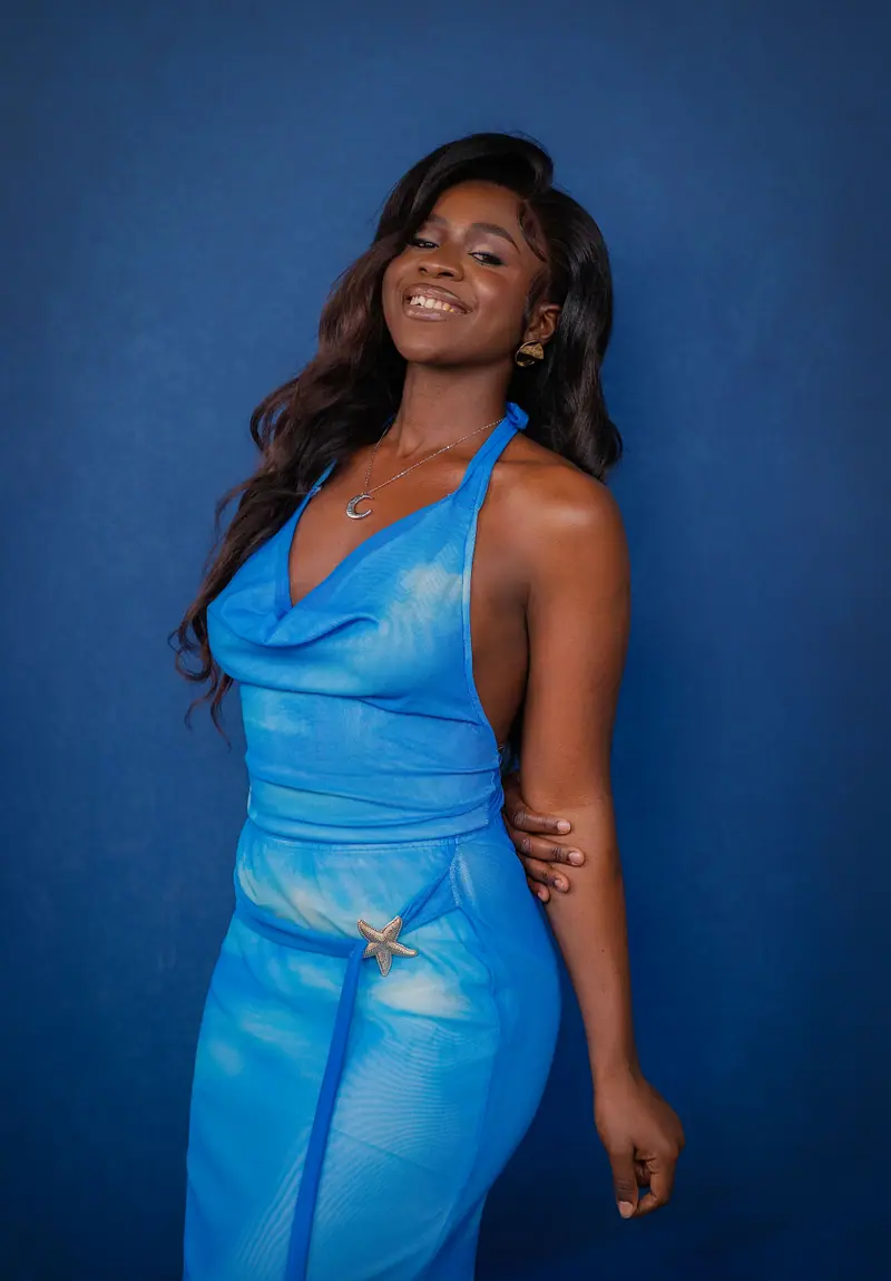 Smiling woman in a blue halter dress against a navy backdrop
