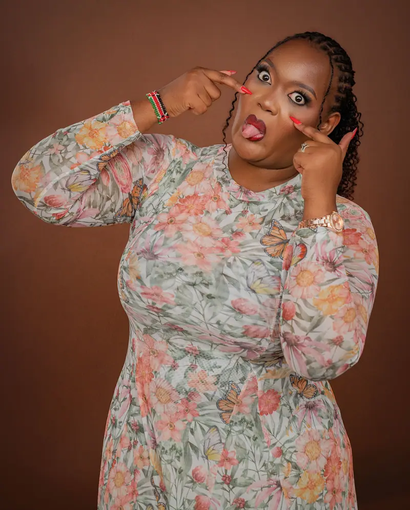 Woman in a floral dress pulling a playful face against a brown backdrop
