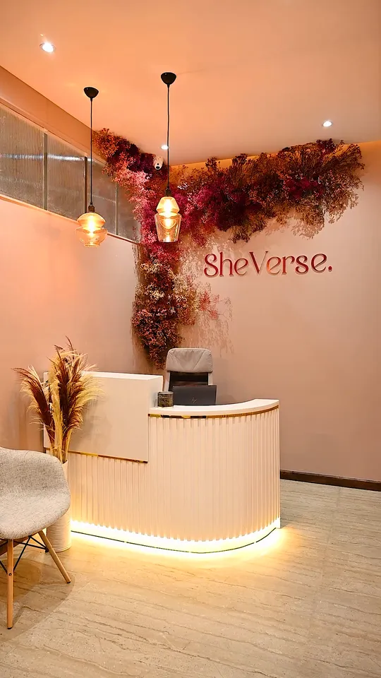 The SheVerse reception, with the logo on a pink wall under a canopy of dried flowers